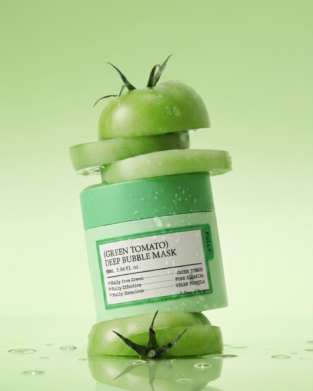 A green tomato-shaped deep bubble mask bottle with sliced tomato props, photographed on a light green background with water droplets and a reflective surface.