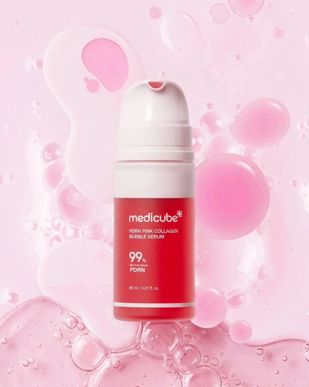 A bottle of medicube Pink Collagen Bubble Serum centered against a pink background with liquid droplets and bubbles. The bottle is red and white with the brand name 'medicube' and product text clearly visible.