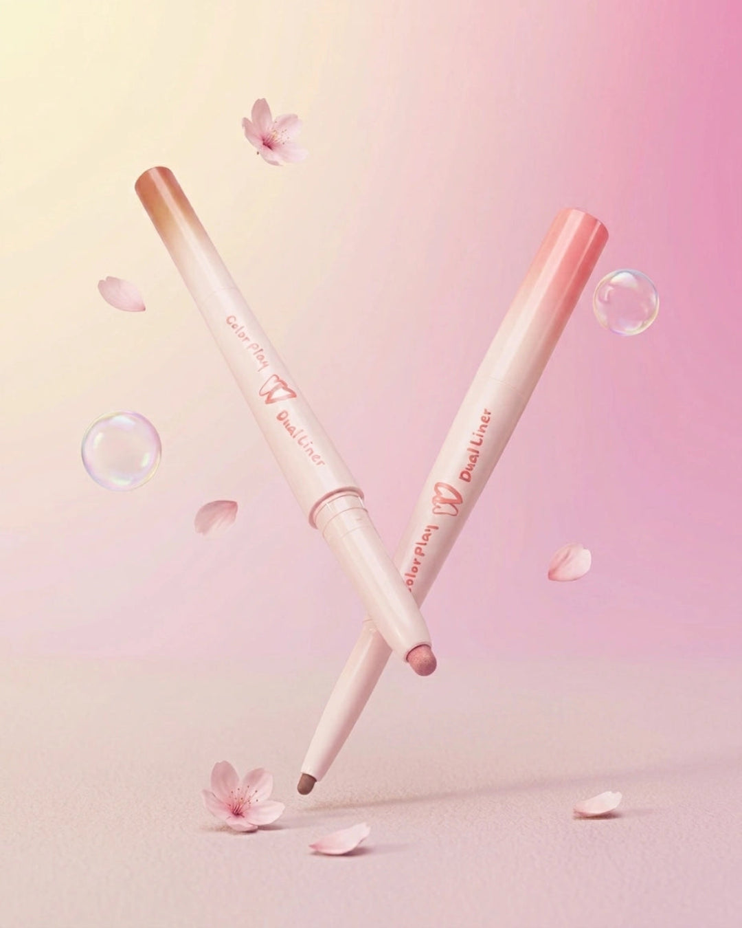 Two pink and white dual-ended lip liner pencils crossed on a soft pink background with floating cherry petals and bubbles. The brand name 'Shapppa' and 'DualLiner' are visible on the packaging.