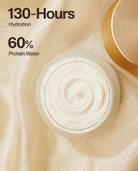 Open jar of white cream with its gold lid resting beside it on a draped beige fabric background, with text reading '130-Hours Hydration' and '60% Protein Water'.