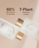Two frosted white cosmetic bottles with metallic gold caps on a soft beige background, with text reading '60% Milk Ceramide for Hydrating' and '7-Plant Brightening Complex.'.