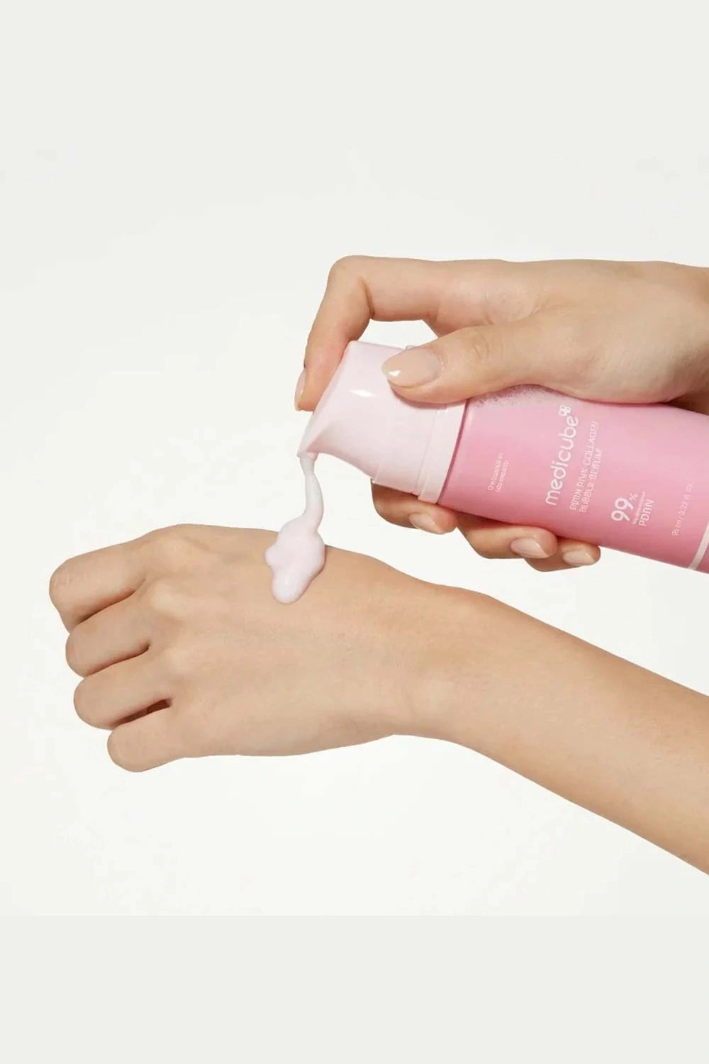 Person applying pink sunscreen cream to their hand on a white background