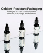 Three small dark dropper bottles labeled 5+ arranged on a reflective surface with text above reading 'Oxidant-Resistant Packaging' and 'Packaged in a dark bottle to protect the formula from light and oxidation.'.