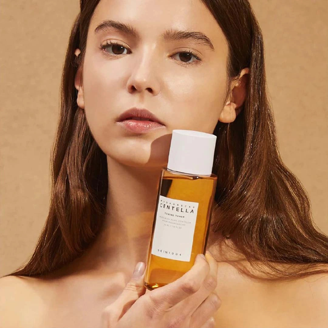 Woman holding a bottle of Skinceuticals Centella product against a beige background