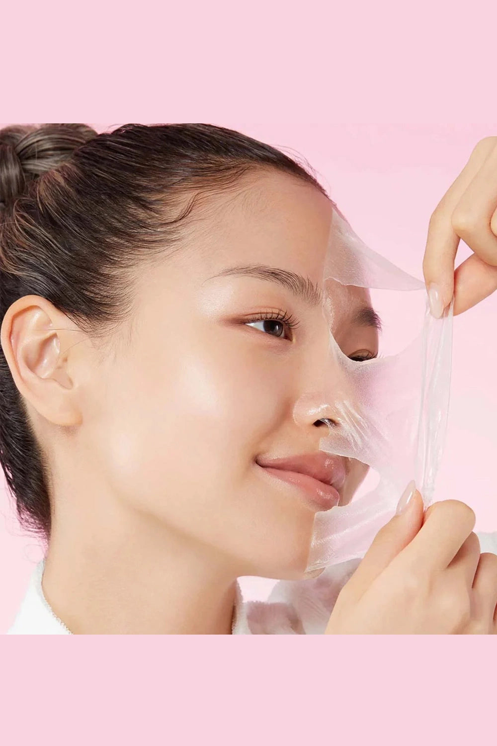 Person applying a face mask with a pink background