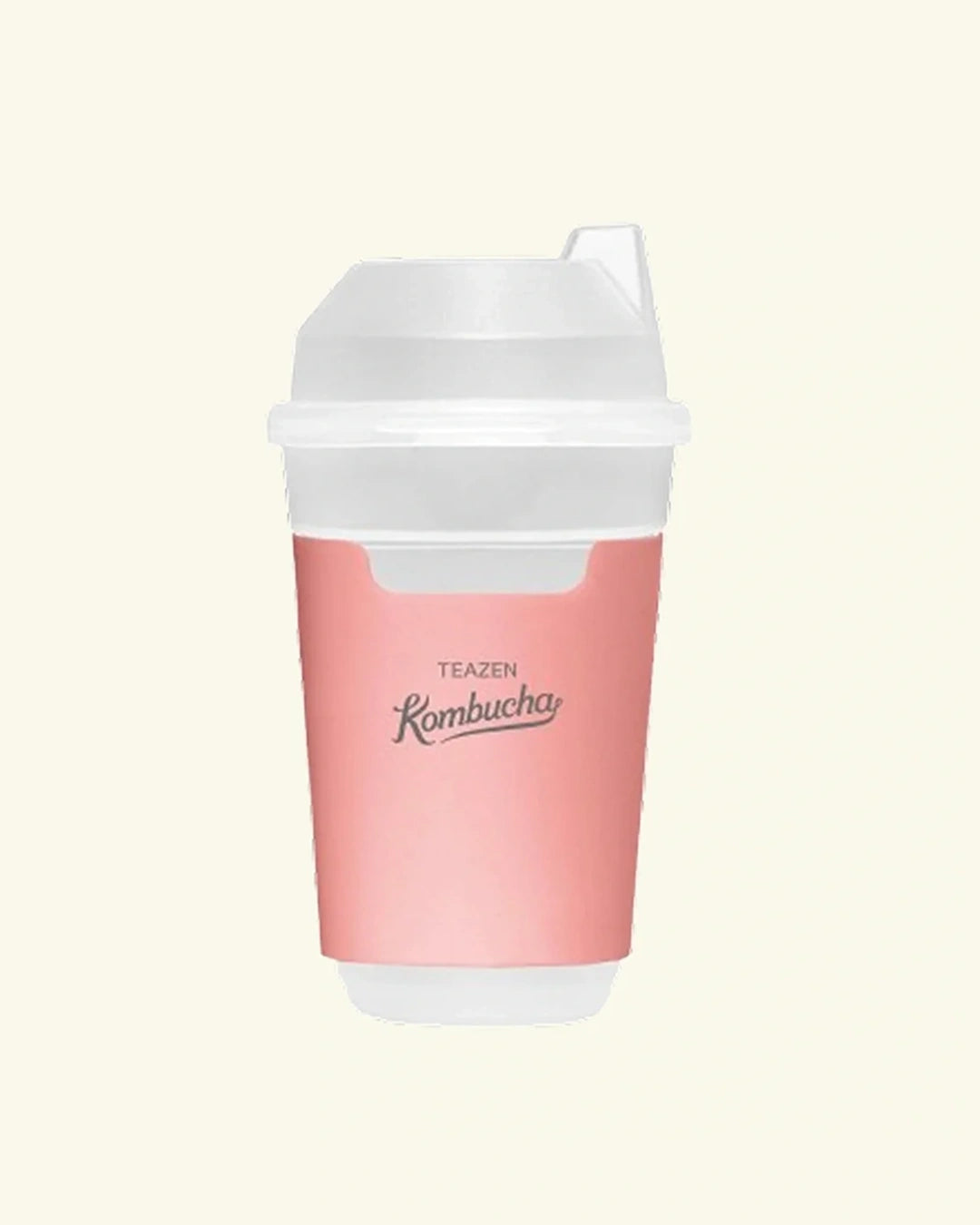 A reusable travel tumbler with a pink body and a white lid, featuring the brand name 'TEAZEN' and 'Kombucha' printed on the front, set against a solid cream background.