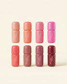 Eight small cylindrical cosmetic tubes arranged in two rows of four on a warm off-white background. The tubes come in shades of peach, coral, pink, mauve, and burgundy, with the brand name 'Drew Filter' printed vertically in white on each tube.